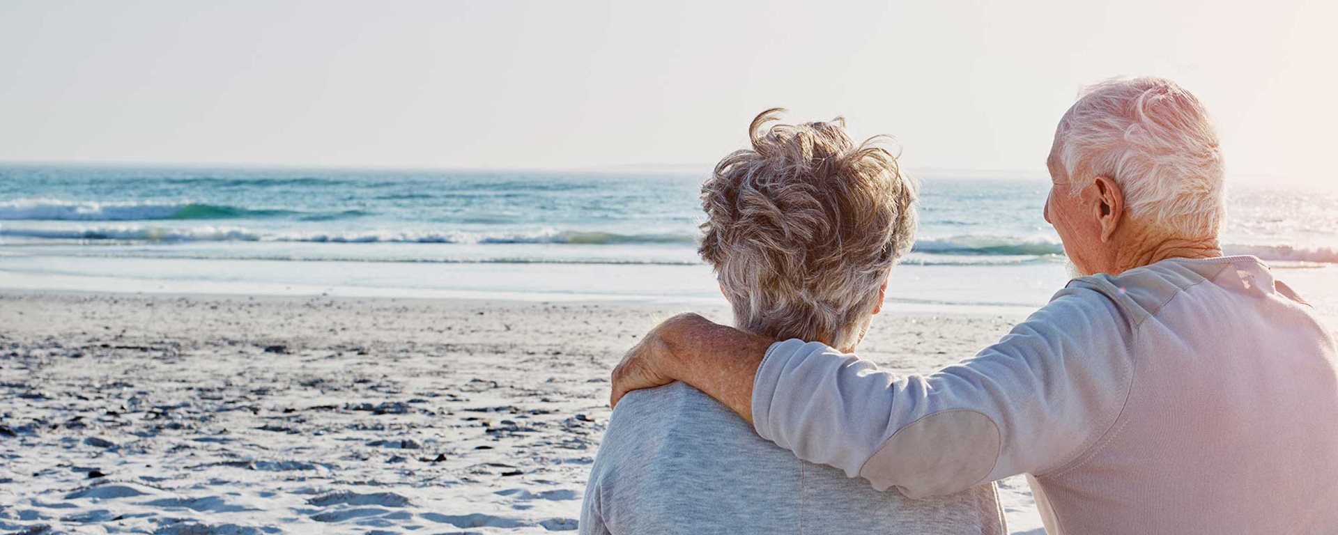 Old couple standing on beach looking toward the ocean